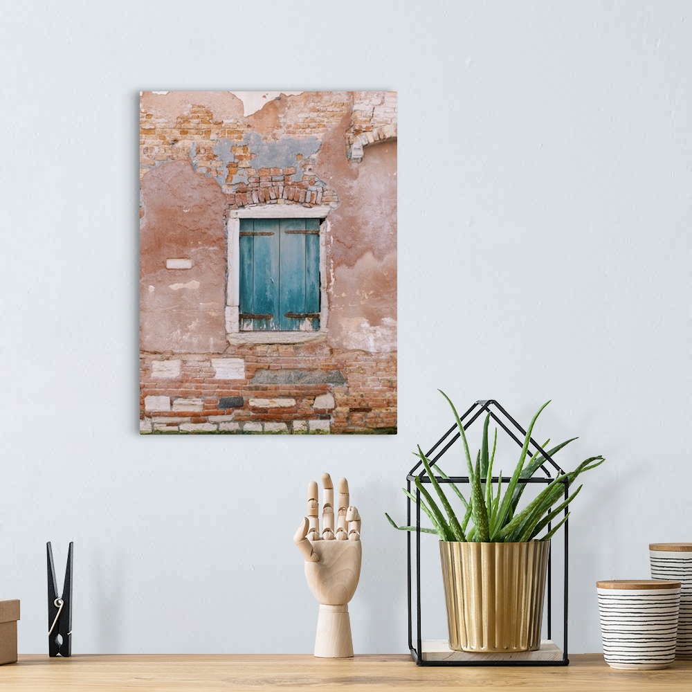 A bohemian room featuring An architectural photograph of a set of small blue shutters set in a rustic brick and stucco wall...