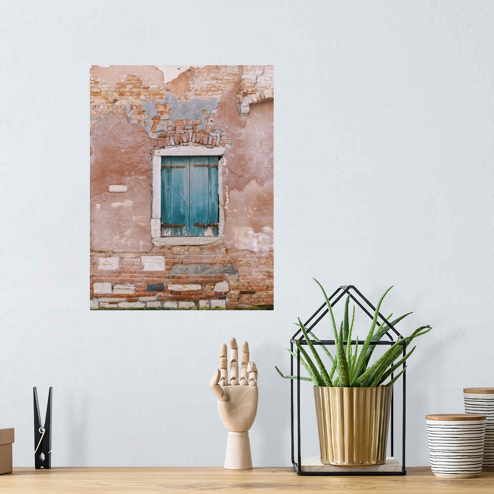 A bohemian room featuring An architectural photograph of a set of small blue shutters set in a rustic brick and stucco wall...