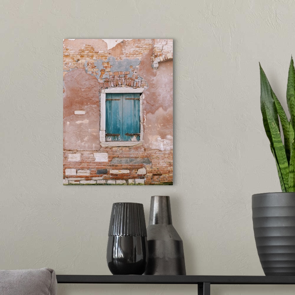 A modern room featuring An architectural photograph of a set of small blue shutters set in a rustic brick and stucco wall...