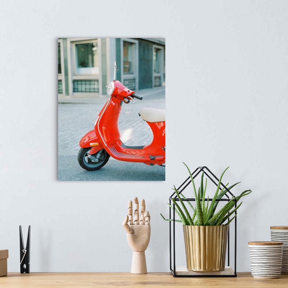 A bohemian room featuring A photograph of a red scooter parked on the street.