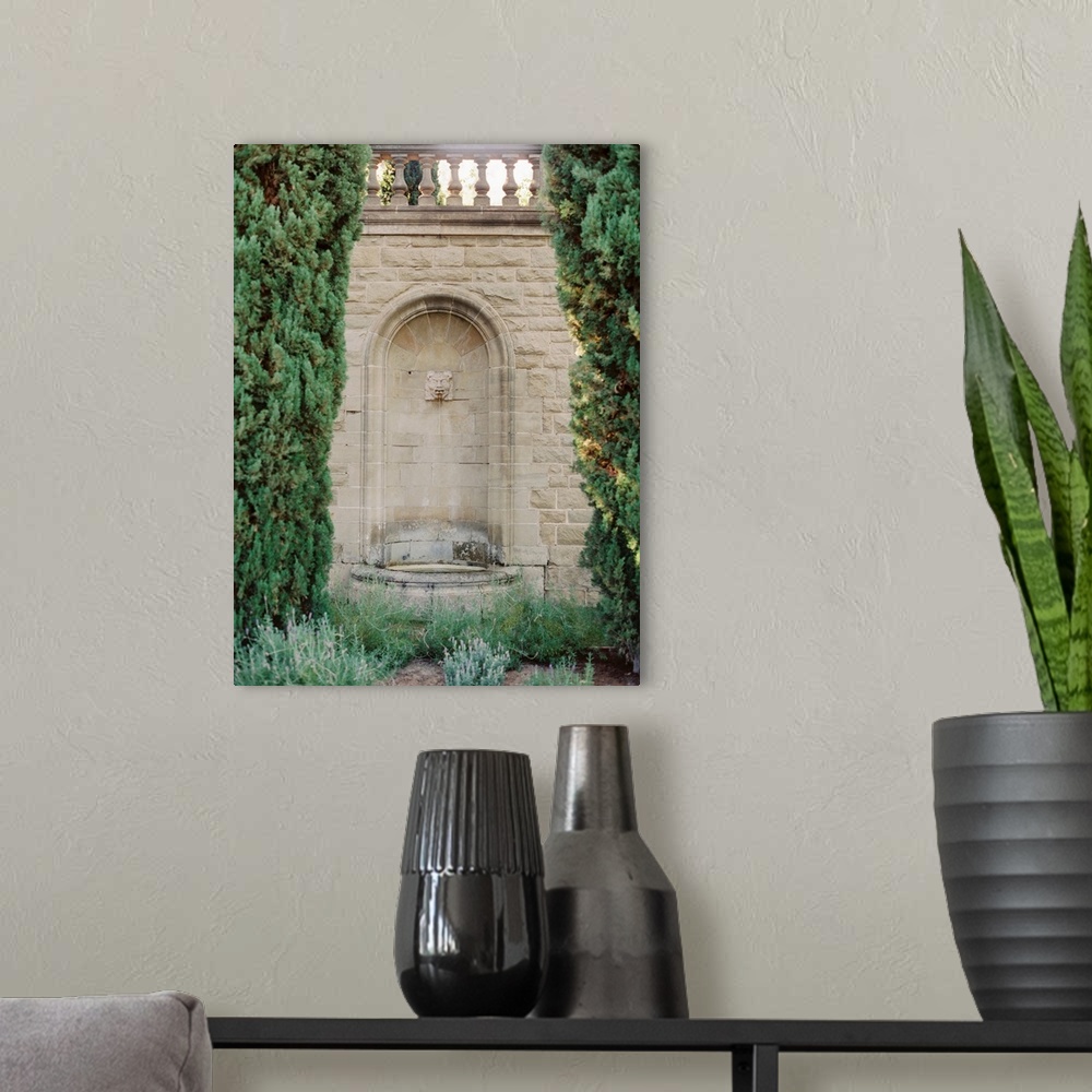 A modern room featuring A photograph of an ornate fountain set into the wall amidst elegant gardens of a Mediterranean vi...