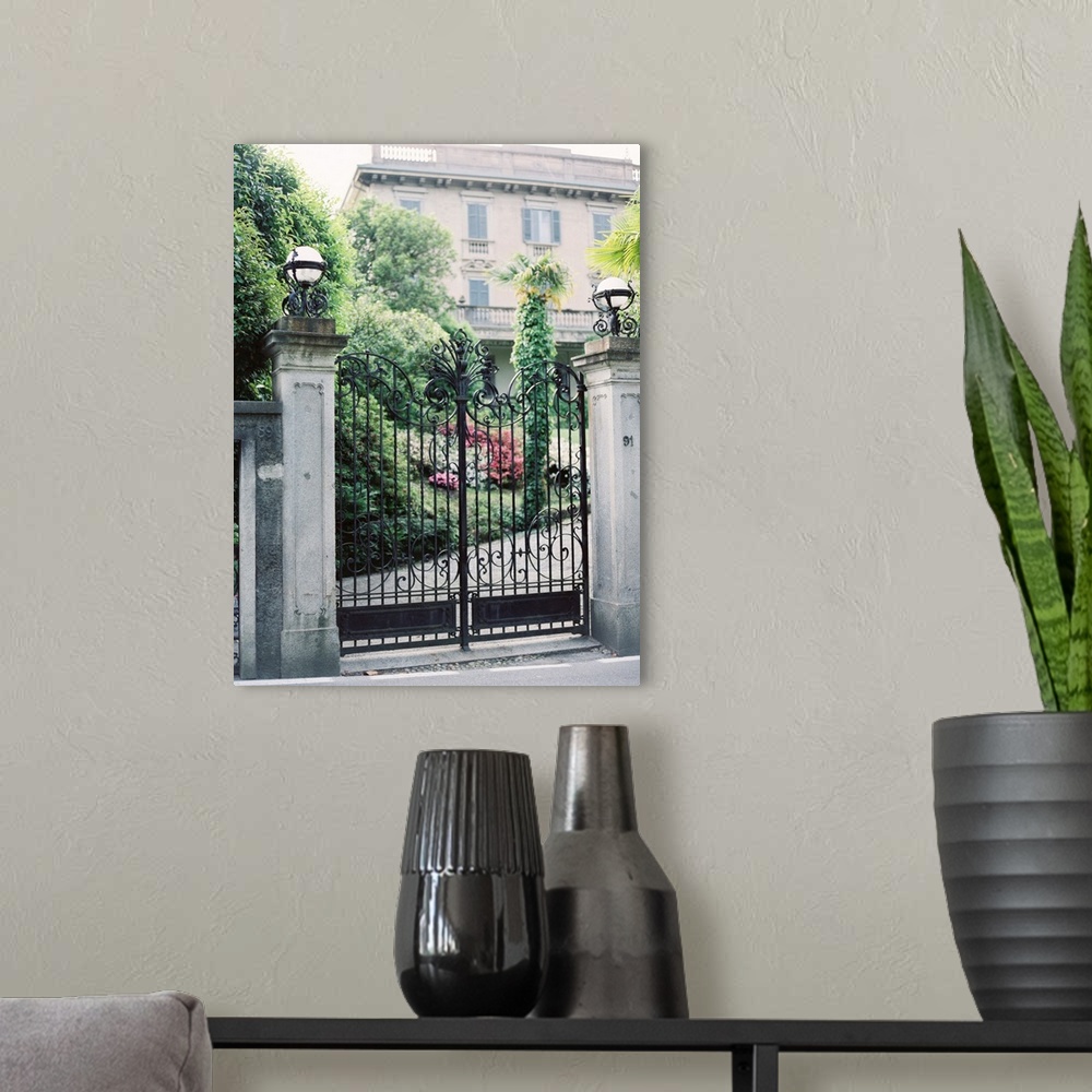 A modern room featuring A photograph of a pair of ornate iron gates in front of a mediterranean villa.