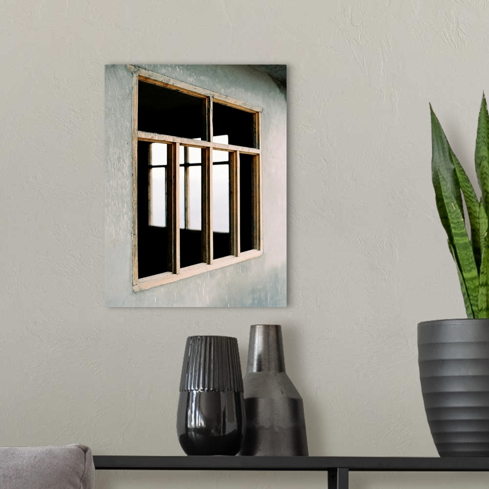 A modern room featuring A poetic photograph of simple wooden window frames in a stucco wall.