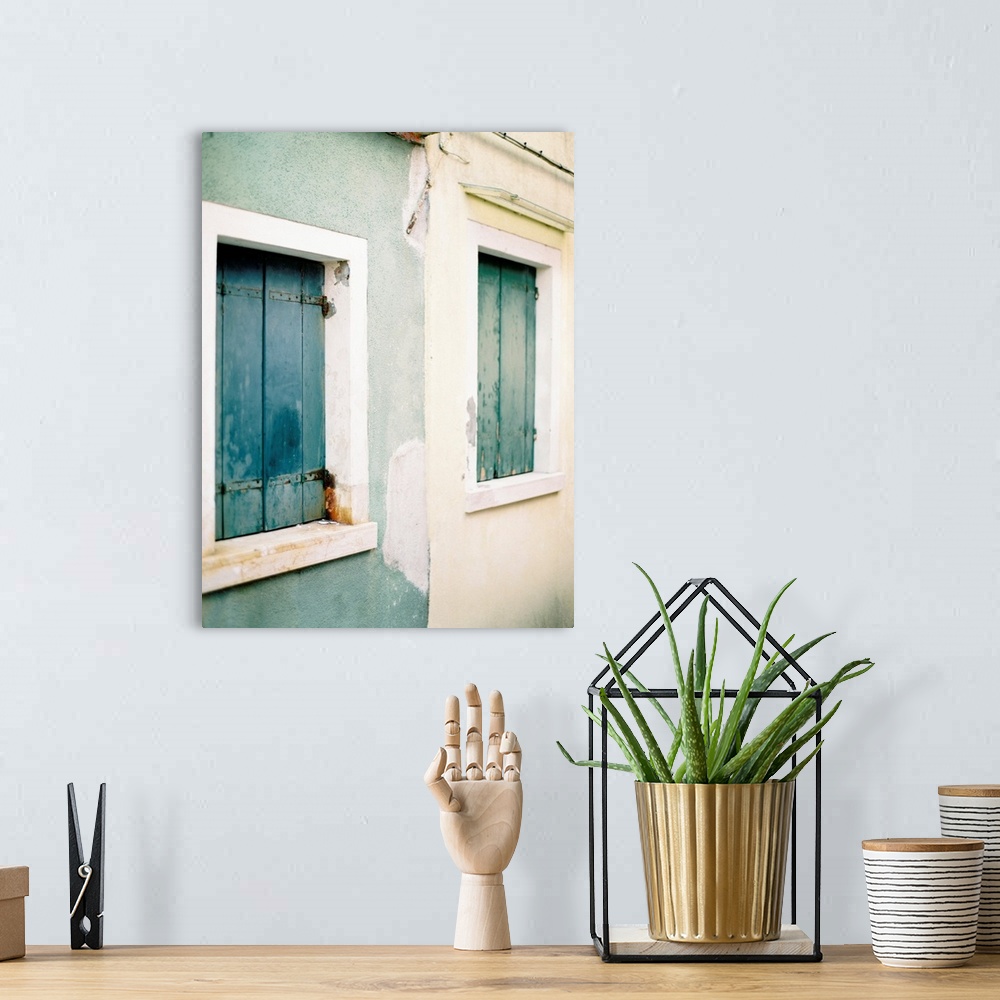 A bohemian room featuring Photograph of a blue house next to a white house, both with old wooden shutters, Burano, Italy.