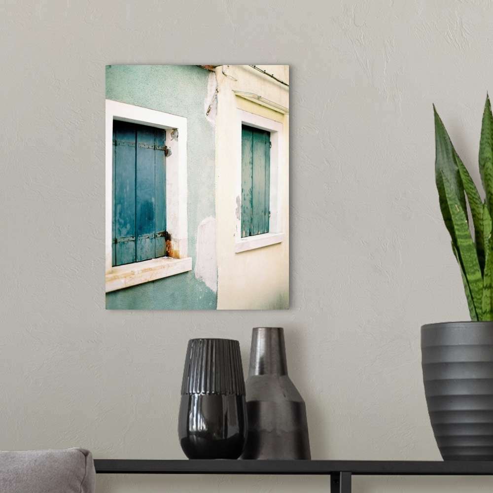 A modern room featuring Photograph of a blue house next to a white house, both with old wooden shutters, Burano, Italy.