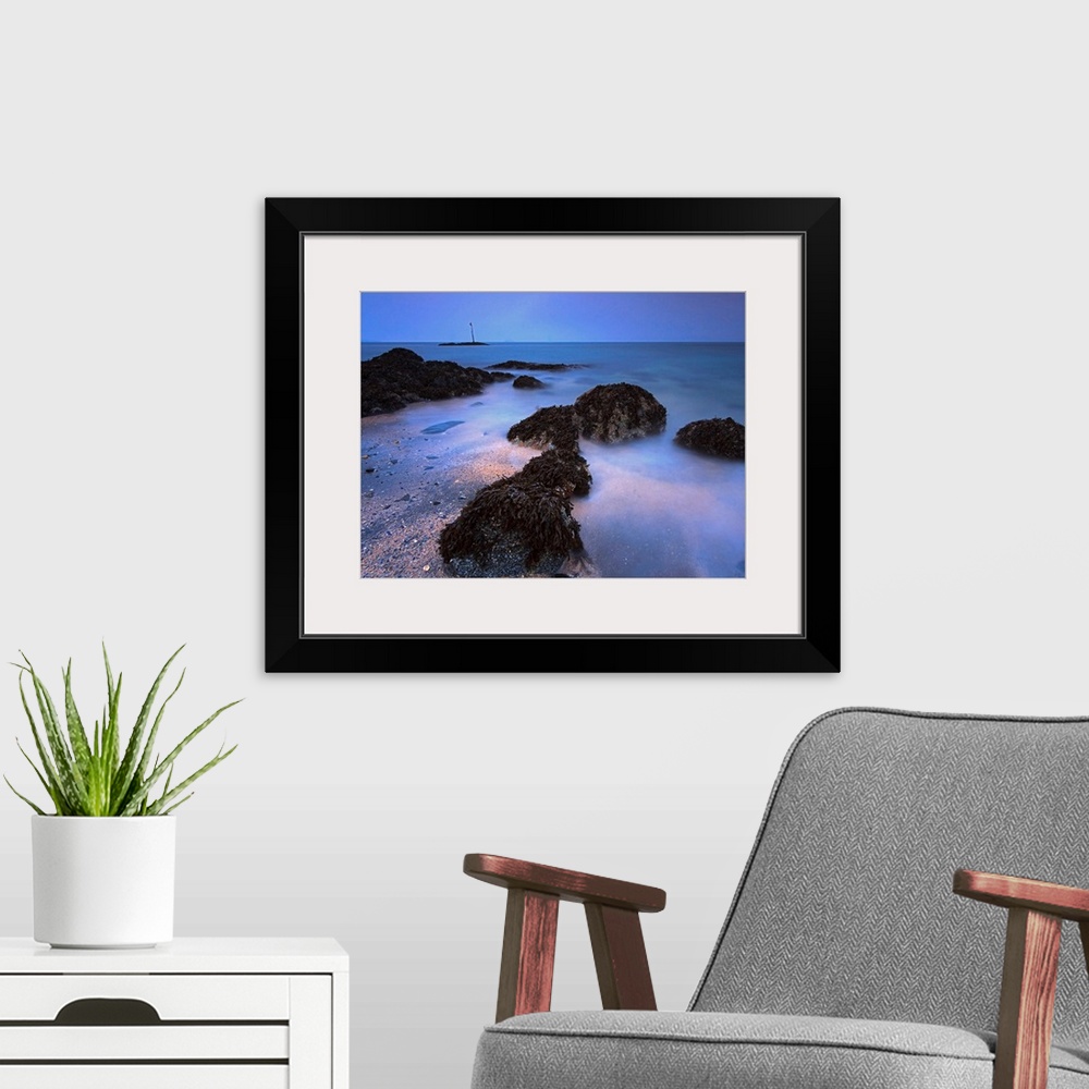 A modern room featuring The landscape wall art is a time lapse photograph of waves washing on shore between kelp covered ...
