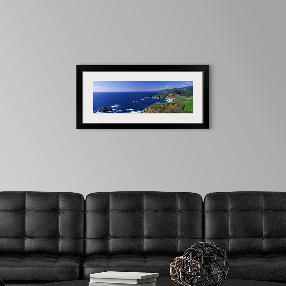 A modern room featuring This wall art is a panoramic photograph of the coastal cliffs and the open ocean beyond.