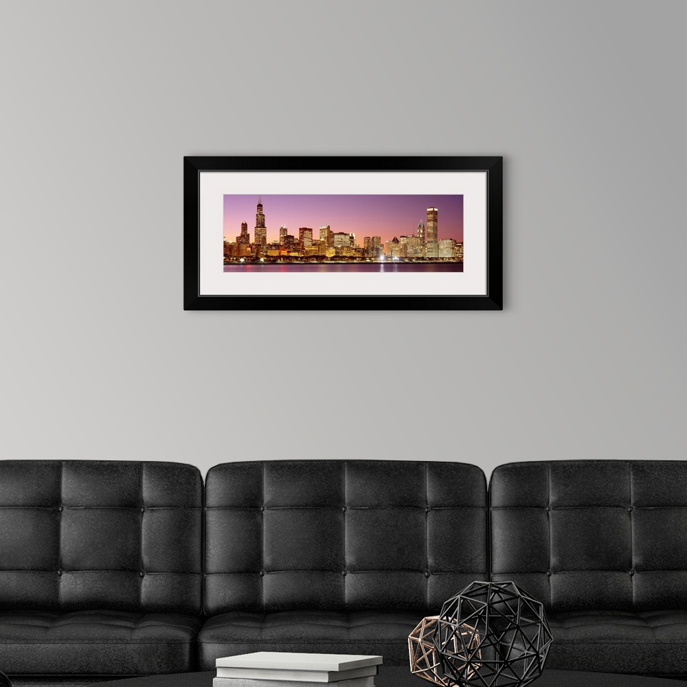 A modern room featuring A panoramic photograph of a skyscraper filled skyline taken at dusk in Chicago, Illinois.  The br...