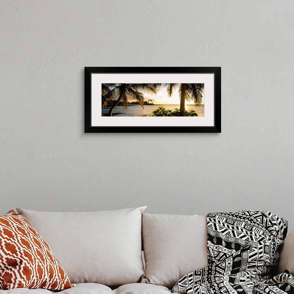 A bohemian room featuring Panoramic wall art photo for the office or home of the Hawaiian coast; palm trees frame the sun s...