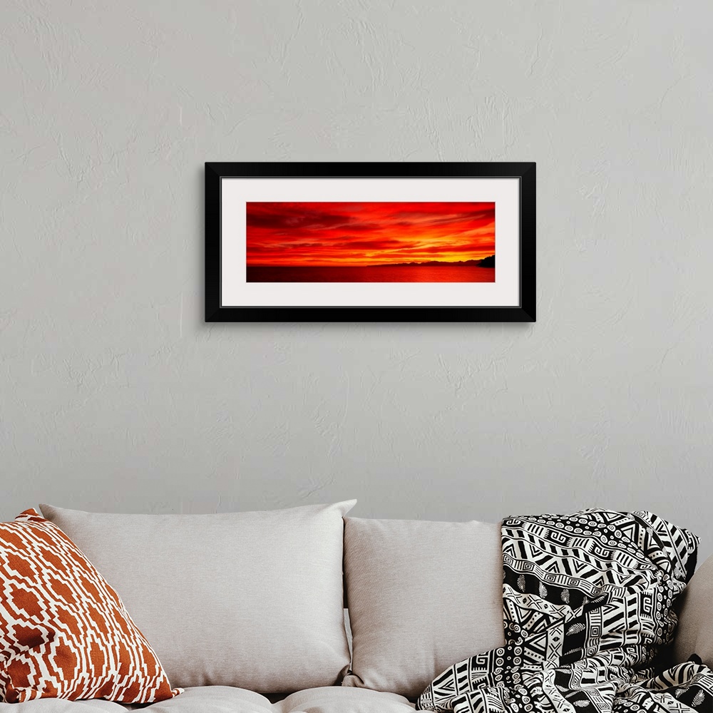 A bohemian room featuring Large wall image of a deep warm sunset over the ocean with a little strip of land on the right si...