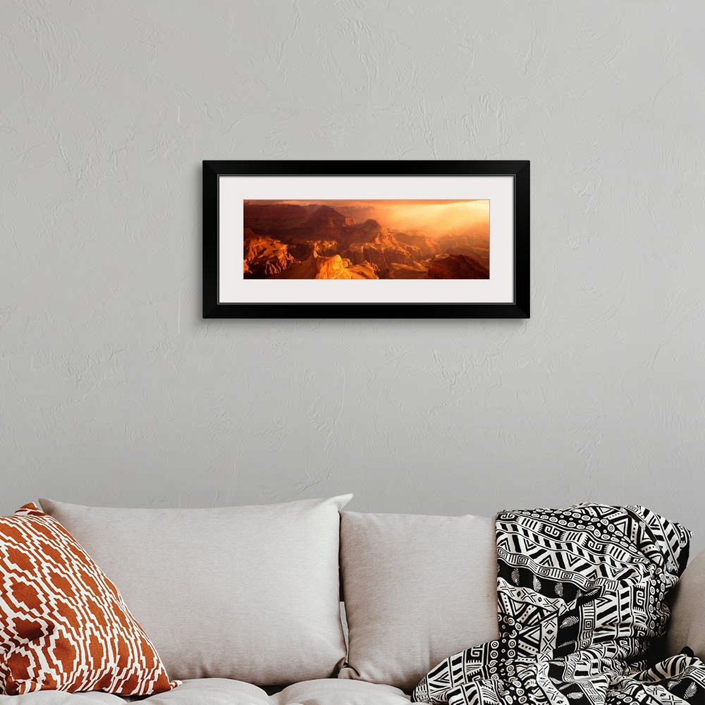 A bohemian room featuring A panoramic photograph of the sunos rays shining on the rocky plateaus emerging from the canyon.