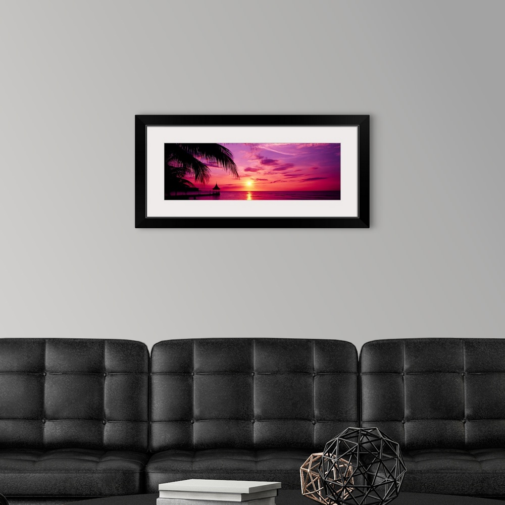 A modern room featuring Panoramic photograph of a colorful sunset on the beach in Montego Bay, Jamaica.  The palm trees a...