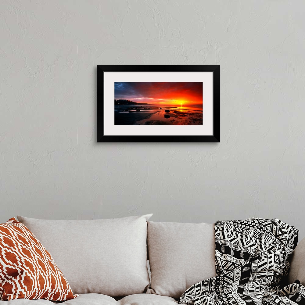 A bohemian room featuring Panoramic photograph that captures a colorful sunset on the shores of England.  The calm beach is...