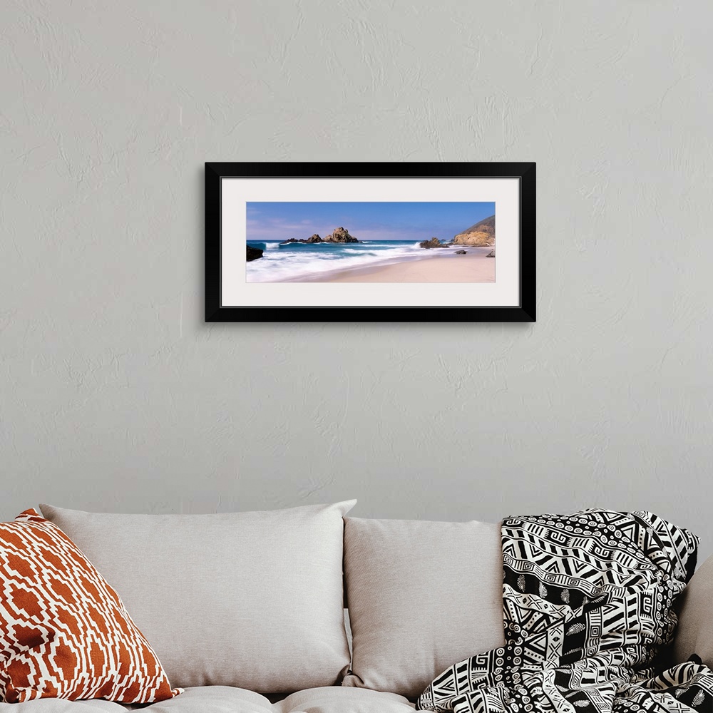 A bohemian room featuring Panoramic photographs displays the Pacific Ocean crashing into the sandy shores of this beach.  L...