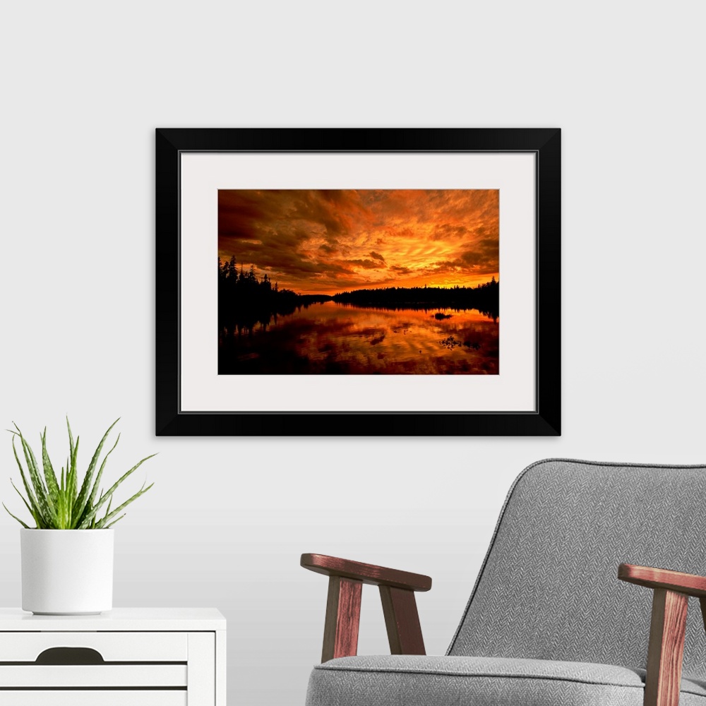 A modern room featuring Horizontal photograph from the National Geographic Collection of a golden sunset over a lake, und...