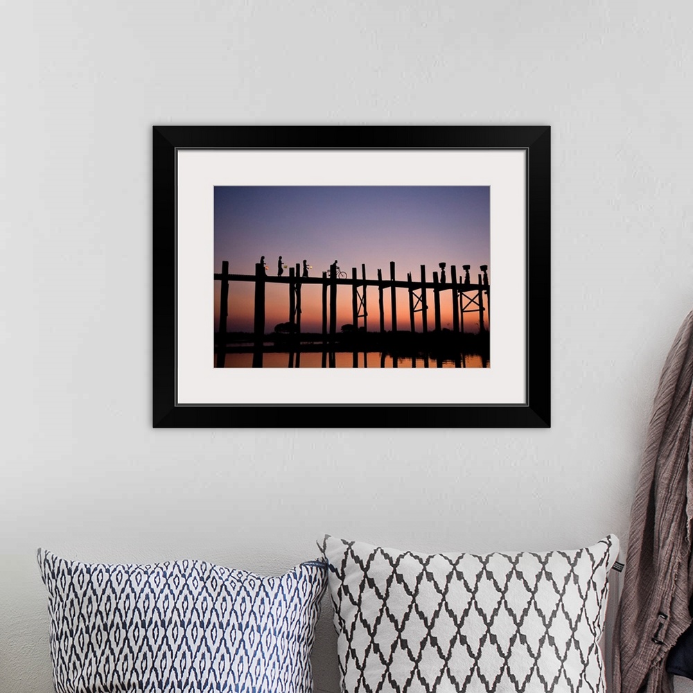 A bohemian room featuring Photograph of people walking and biking across a bridge made of tall wooden beams over the ocean ...