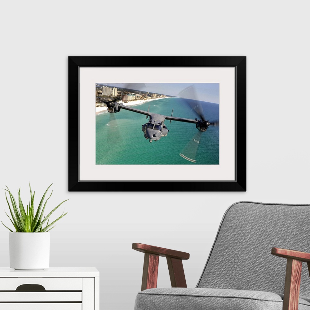 A modern room featuring Large landscape photograph of a CV22 Osprey aircraft flying toward the camera, over the green and...