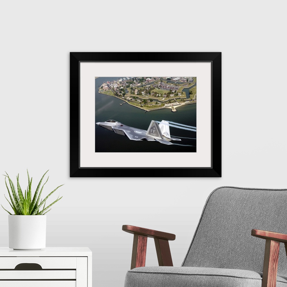 A modern room featuring A militarty fighter jet flies past Fort Monroe with water vapor trails shooting from the wings of...