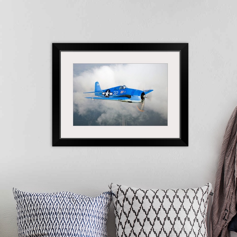 A bohemian room featuring A vintage military aircraft is photographed high in the sky with a large cloud just behind it.