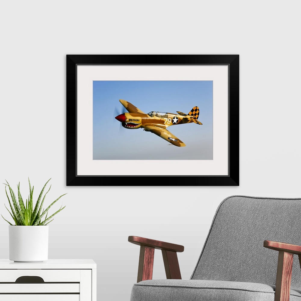 A modern room featuring Landscape photograph on a big canvas of a P-40N Warhawk in flight in a clear blue sky, near Chino...