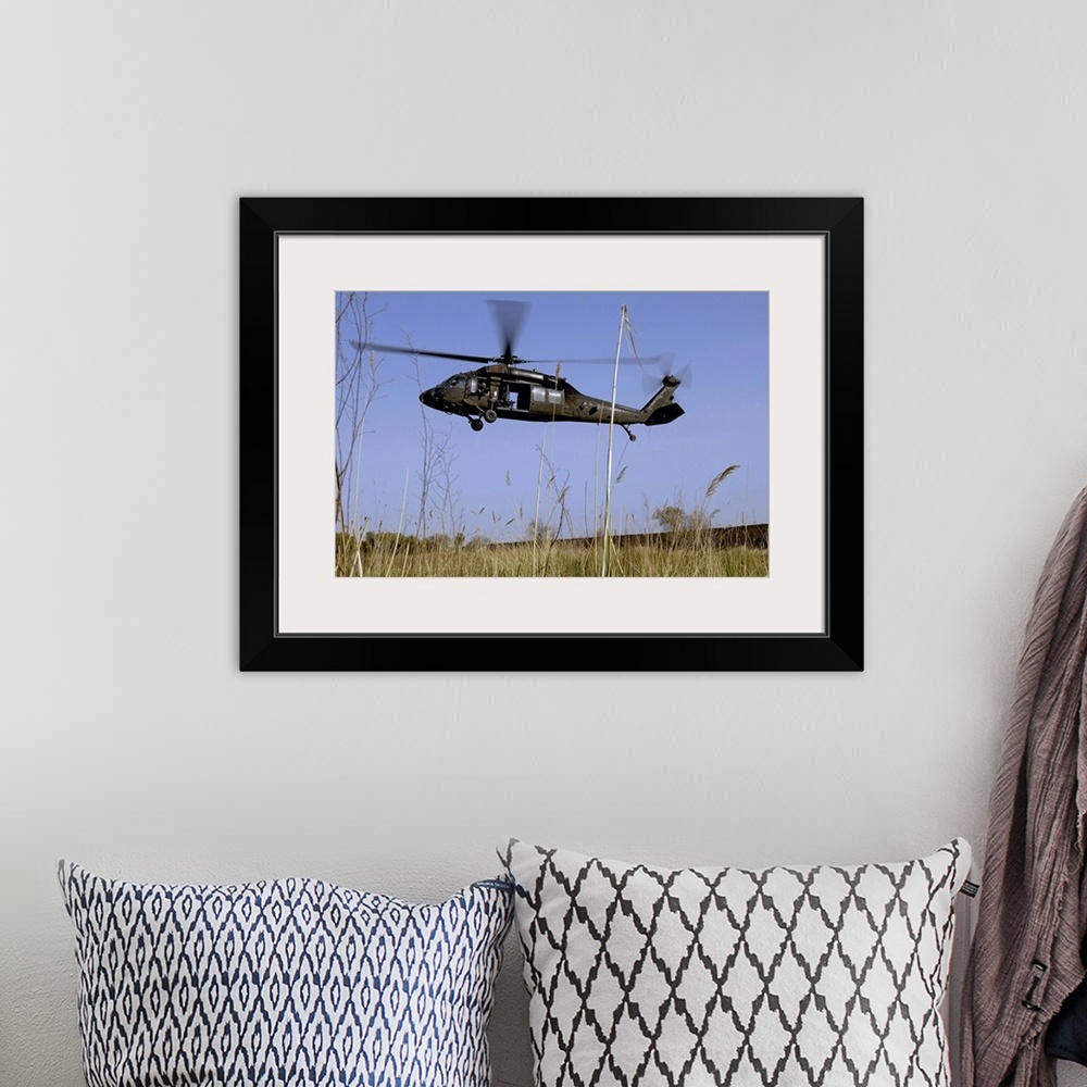 A bohemian room featuring Photograph taken of a helicopter as it lifts off in a tall grass field.