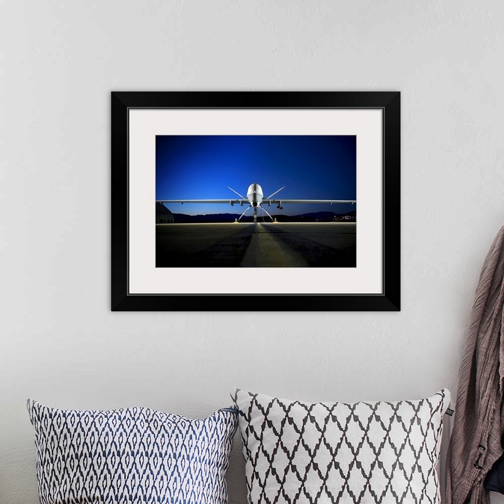 A bohemian room featuring Photograph of airplane on runway with mountain silhouette in the distance at night.