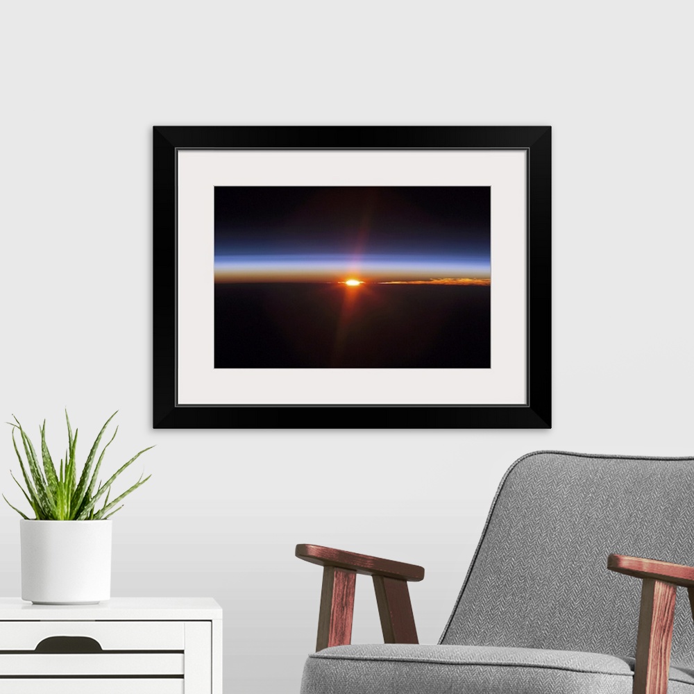 A modern room featuring Aerial photograph of a clear sky at dusk with glowing sun rays.