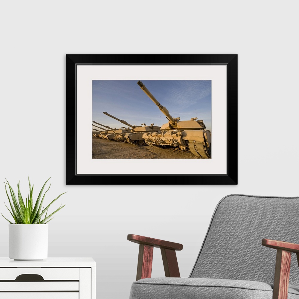 A modern room featuring Photograph taken of large military tanks parked in the desert.