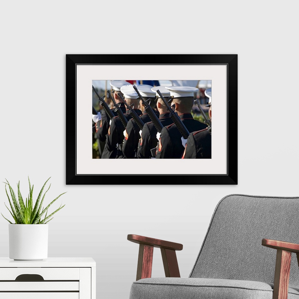 A modern room featuring Big canvas photo of Marines holding rifles lined up facing away from the camera.
