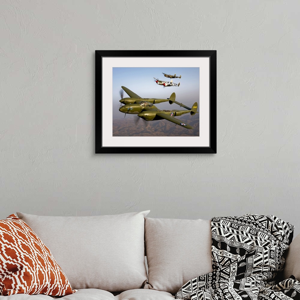 A bohemian room featuring Three vintage military aircrafts are photographed in the sky as they fly high over mountainous te...