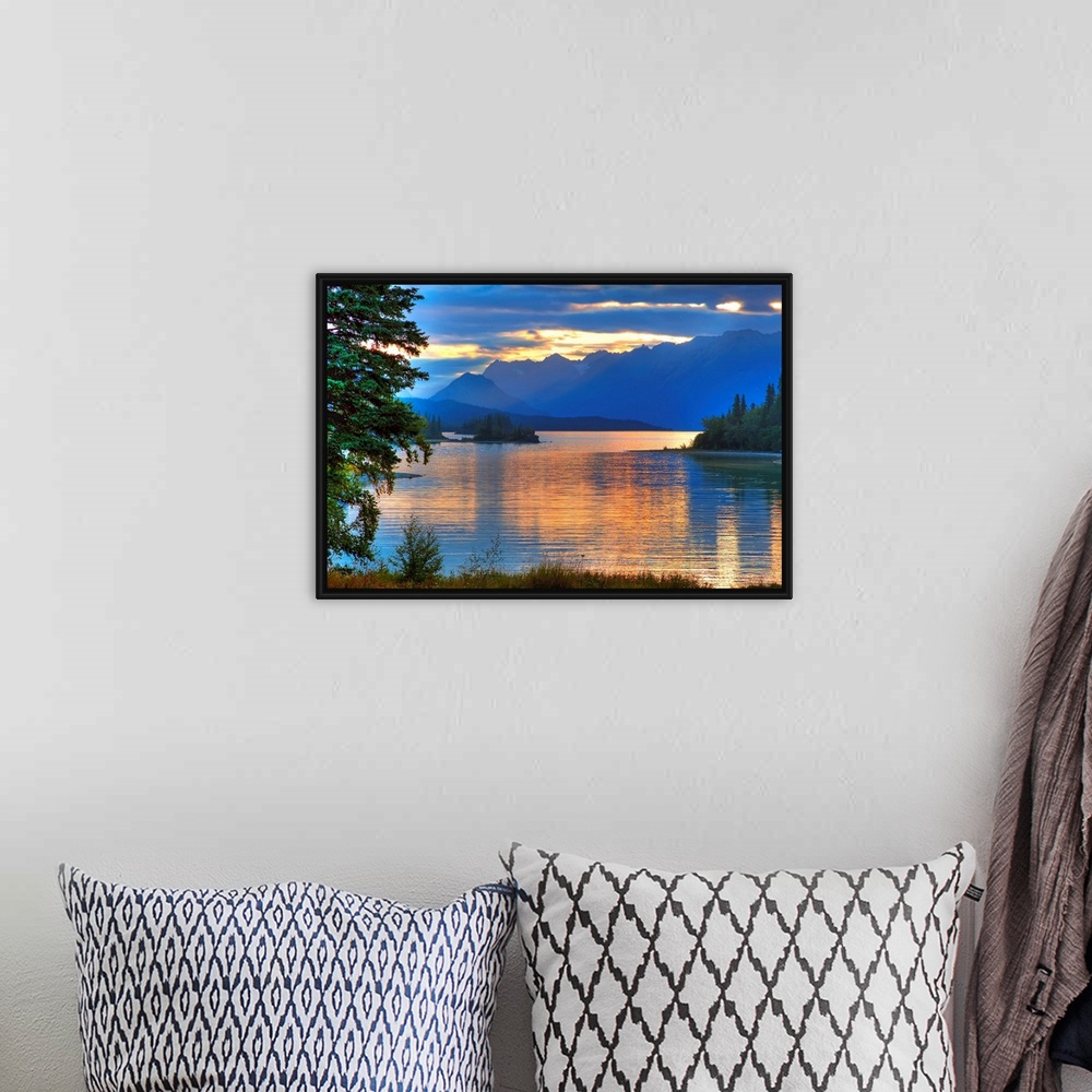 A bohemian room featuring A landscape photograph of morning light reflecting on a lake in the mountains surrounded by trees.