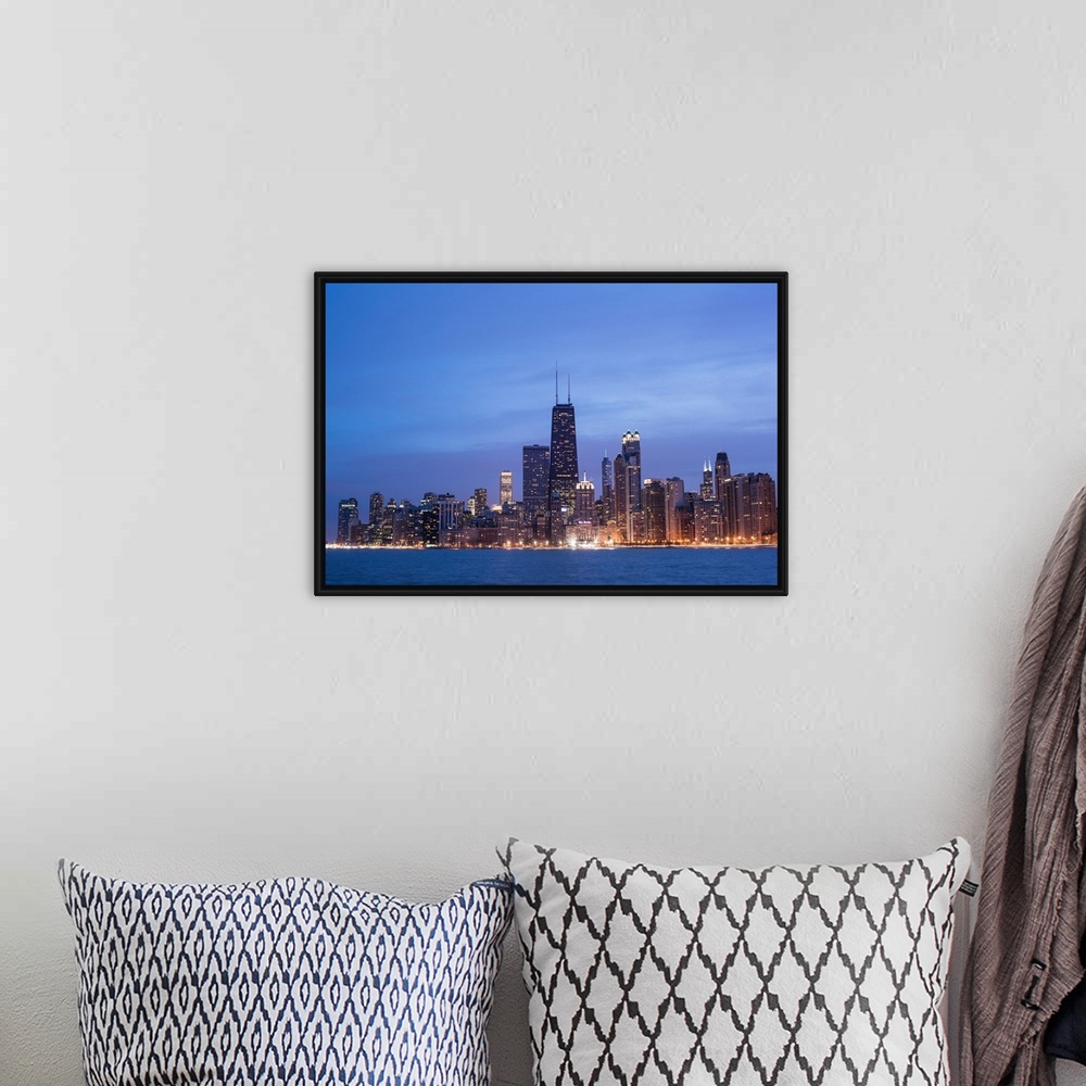 A bohemian room featuring The Chicago city skyline illuminated in the early evening, seen from across the water.