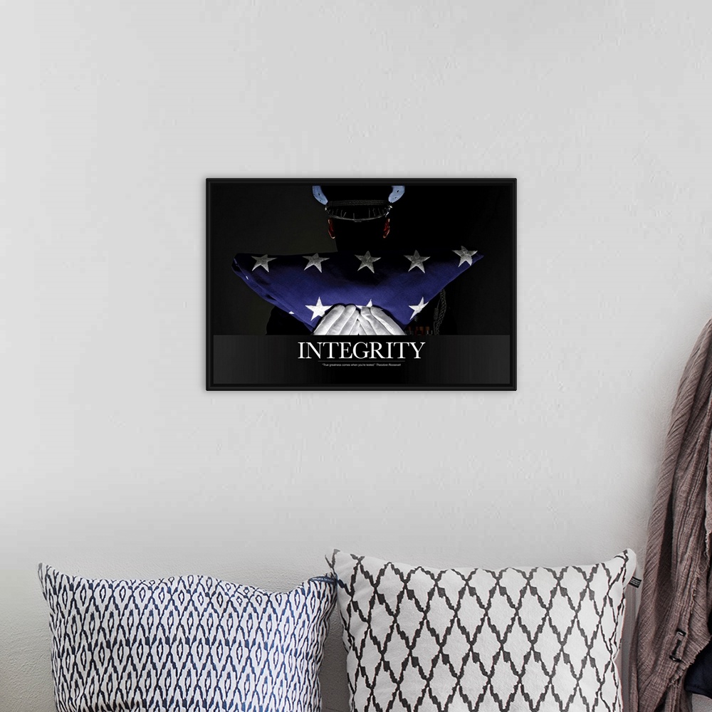 A bohemian room featuring A silhouette of a soldier is shown as he holds up a folded American flag. The word "Integrity" is...