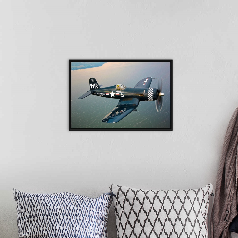 A bohemian room featuring Horizontal photograph of a Vought F4U-5 Corsair in flight over a large body of water, the coastli...