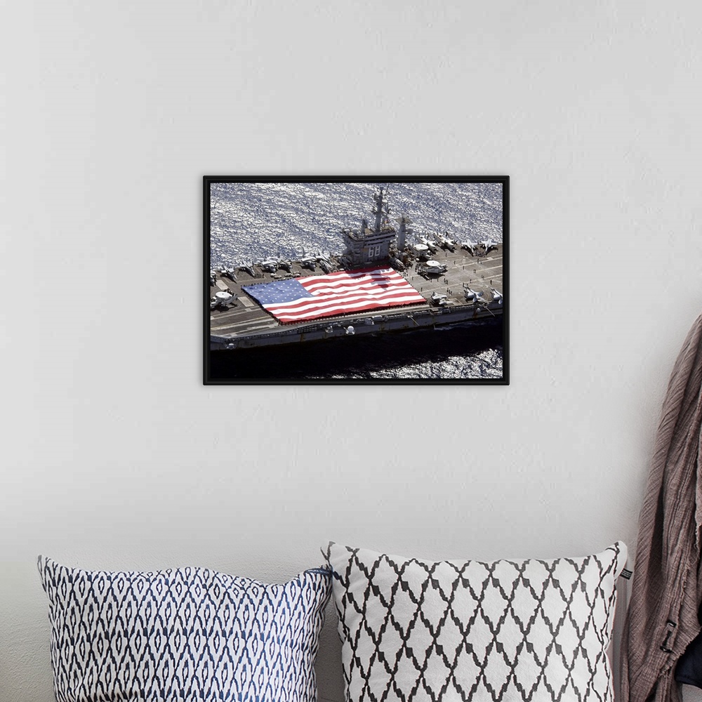 A bohemian room featuring Canvas print of a big American flag being held next to planes sitting on top of a huge navy ship.