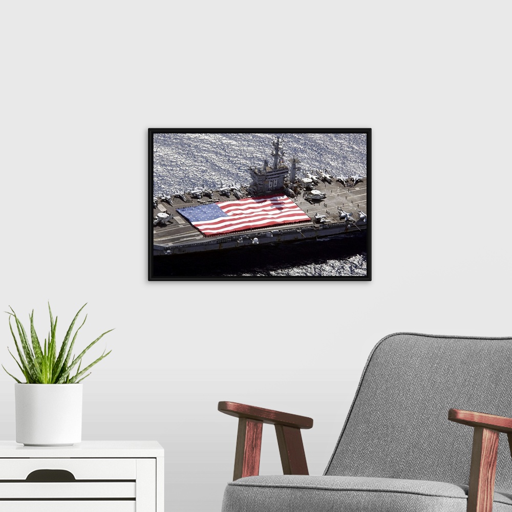 A modern room featuring Canvas print of a big American flag being held next to planes sitting on top of a huge navy ship.
