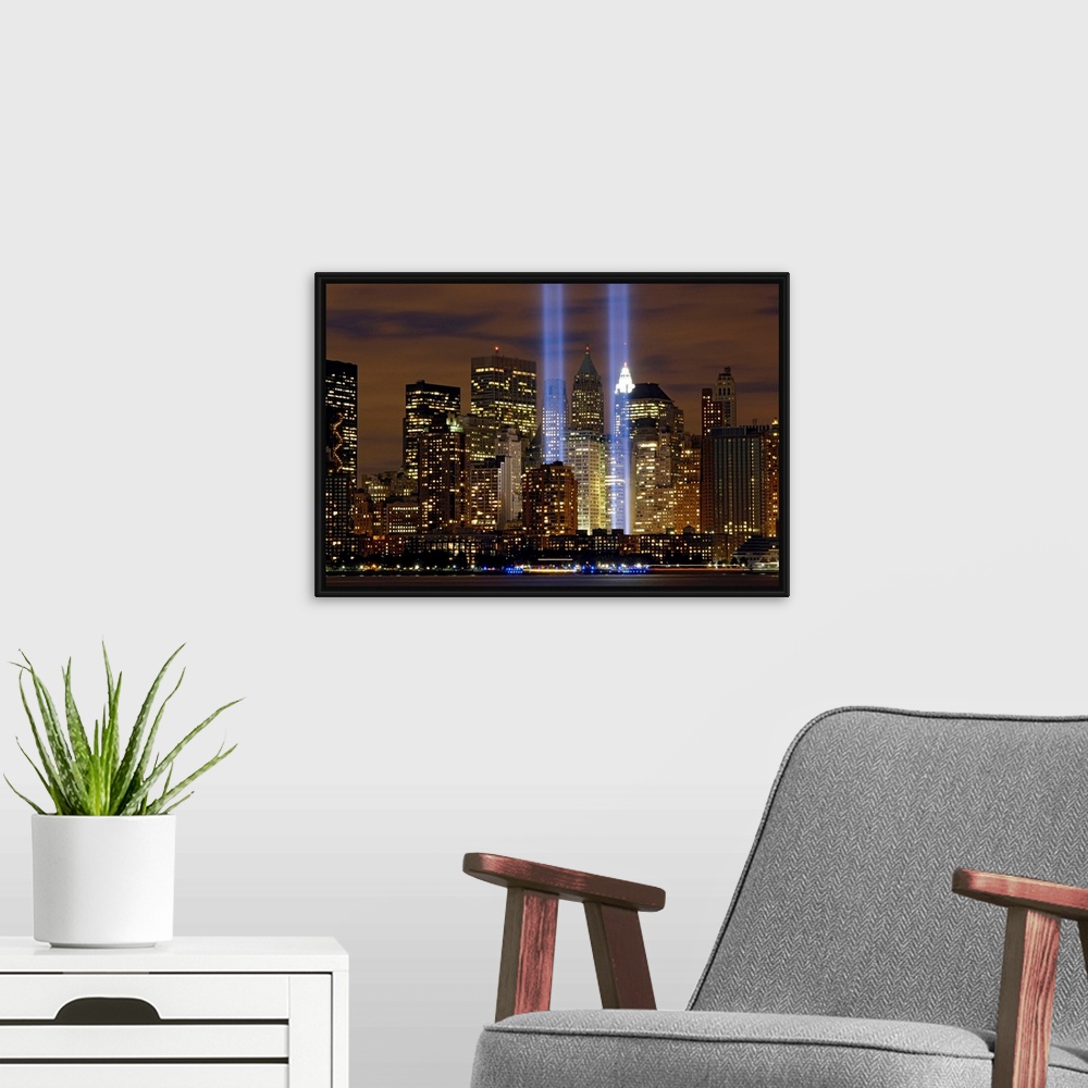 A modern room featuring Two memorial rectangular lights shoot up into the night sky in NY symbolizing the two World Trade...