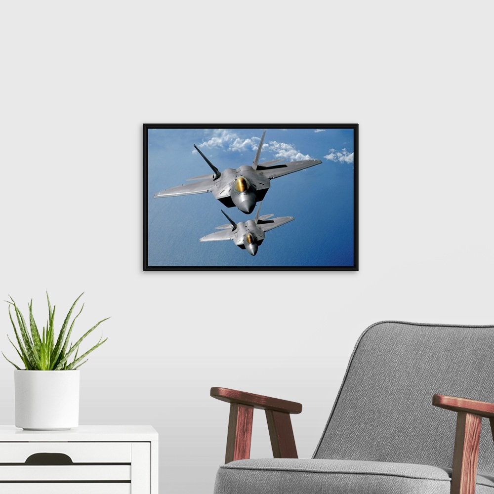 A modern room featuring Large, landscape photograph of two F22 Raptors flying high in the sky above the blue waters of th...