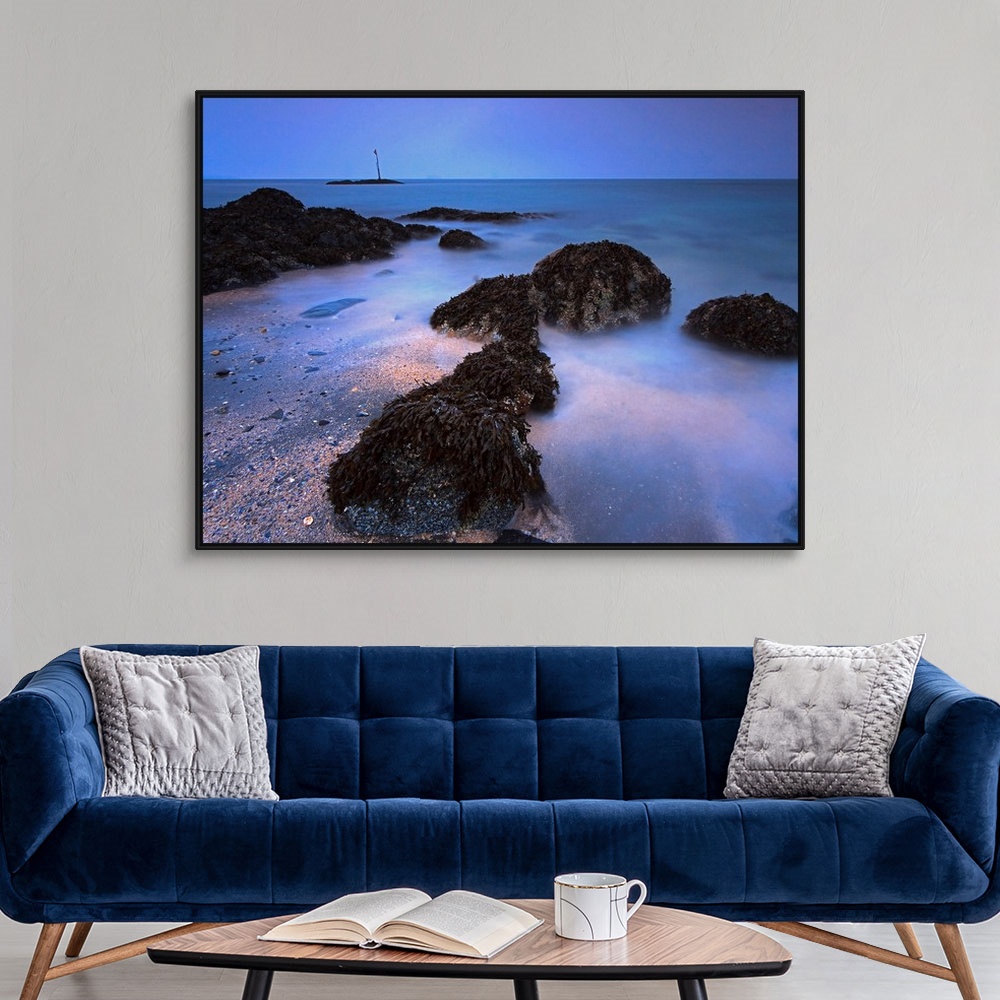 A modern room featuring The landscape wall art is a time lapse photograph of waves washing on shore between kelp covered ...