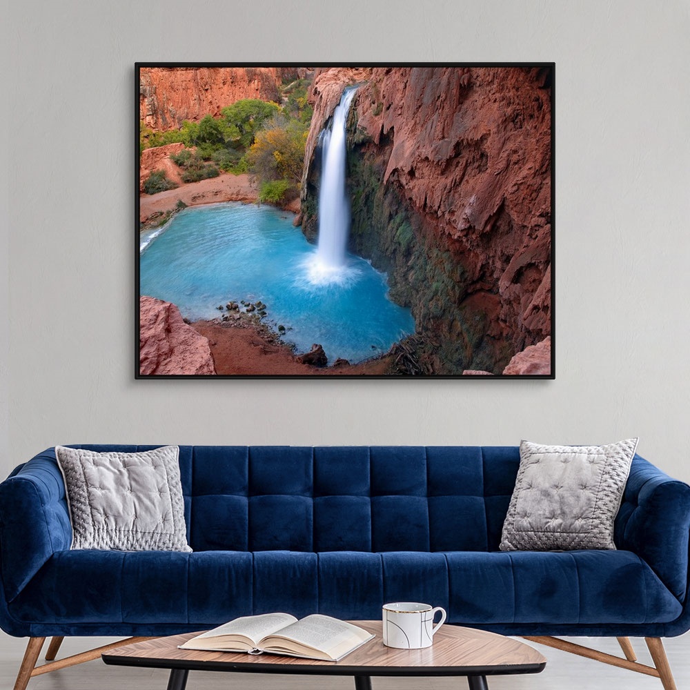 A modern room featuring Large photograph taken of a waterfall crashing into the clear water below.  This portion of the c...