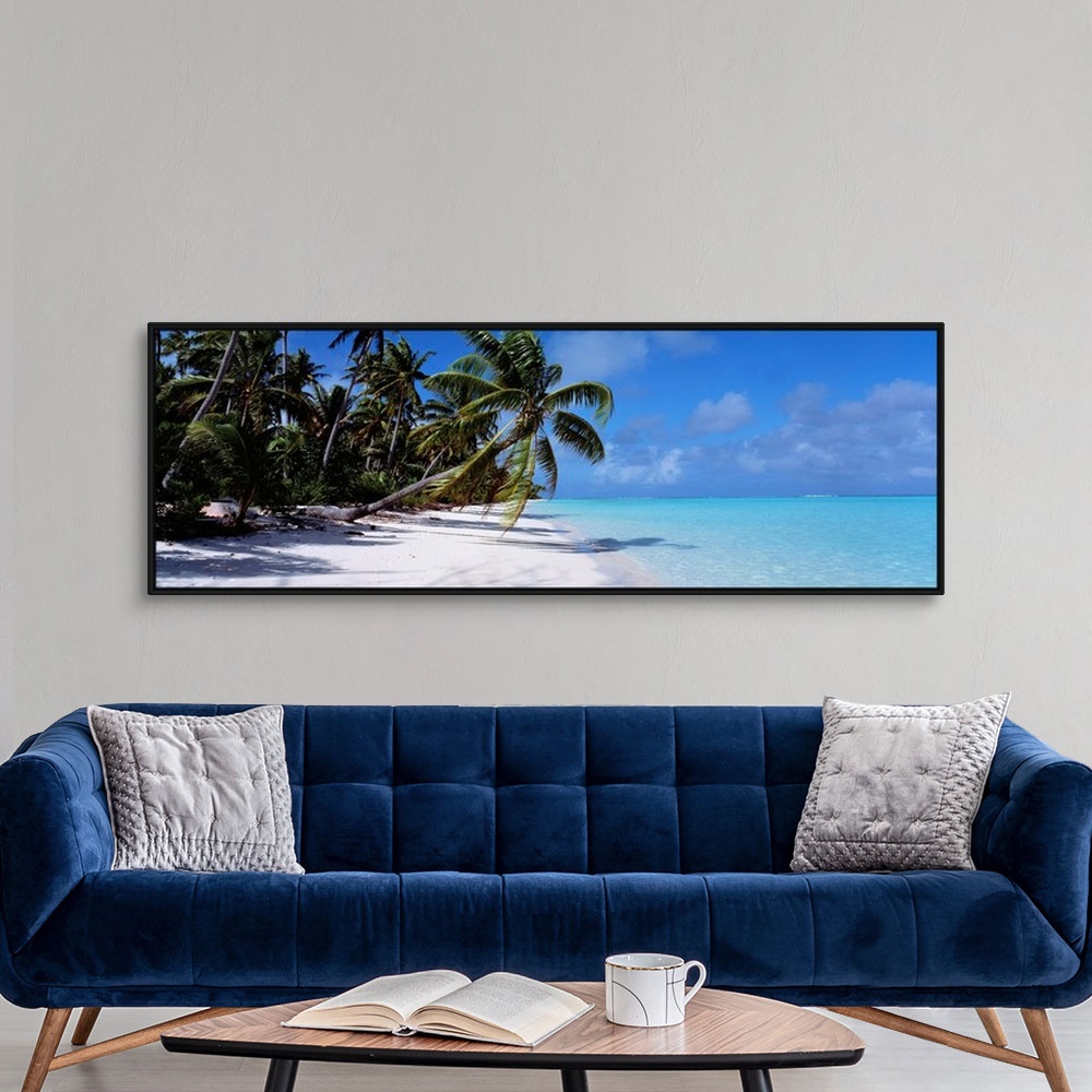 A modern room featuring Panoramic photograph of shoreline covered with palm trees under a cloudy sky.