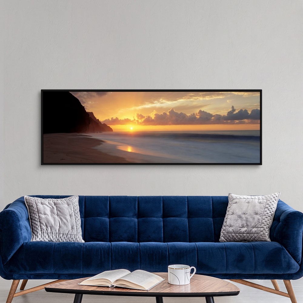 A modern room featuring The sun sinks below the horizon viewed from the beach on a tropical Pacific island.