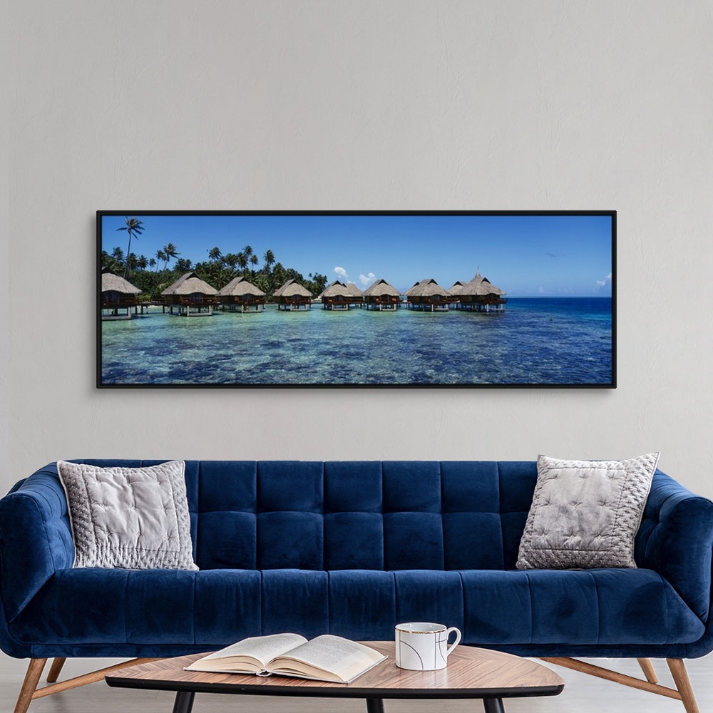 A modern room featuring Panoramic photograph showcases a row of small shacks sitting in the middle of clear water from th...