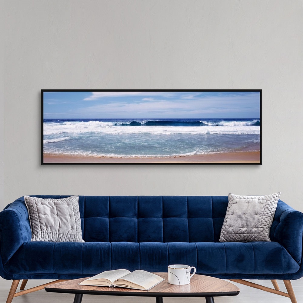 A modern room featuring Panoramic photograph displays the waves of an ocean aggressively crashing into a sandy beach on a...