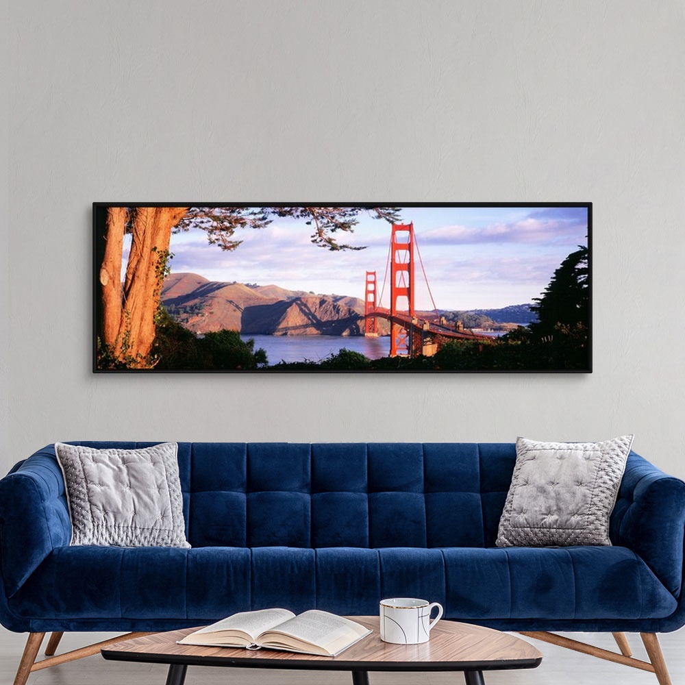 A modern room featuring This panoramic photograph shows a view of the suspension bridge and harbor through a park filled ...