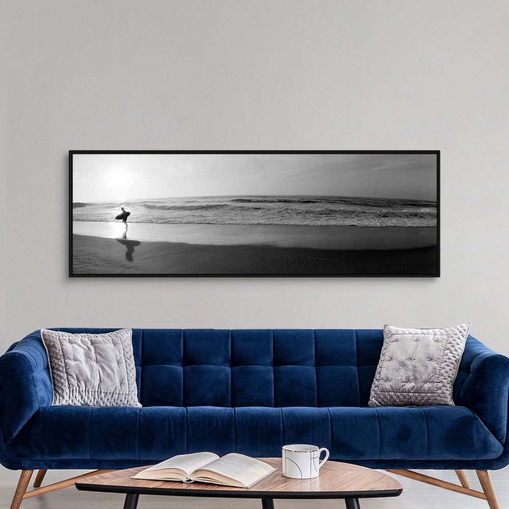 A modern room featuring Panoramic photograph of a surfer walking along a sandy beach in San Diego, California.  The tide ...