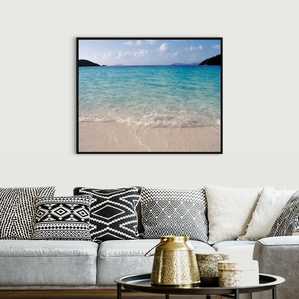 A bohemian room featuring Big photograph focuses on the waves of a cove gently rolling back into sea as a few boats and lan...