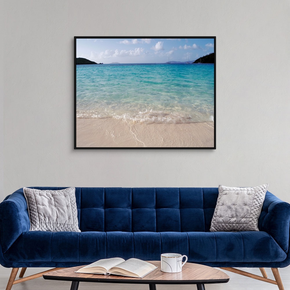 A modern room featuring Big photograph focuses on the waves of a cove gently rolling back into sea as a few boats and lan...